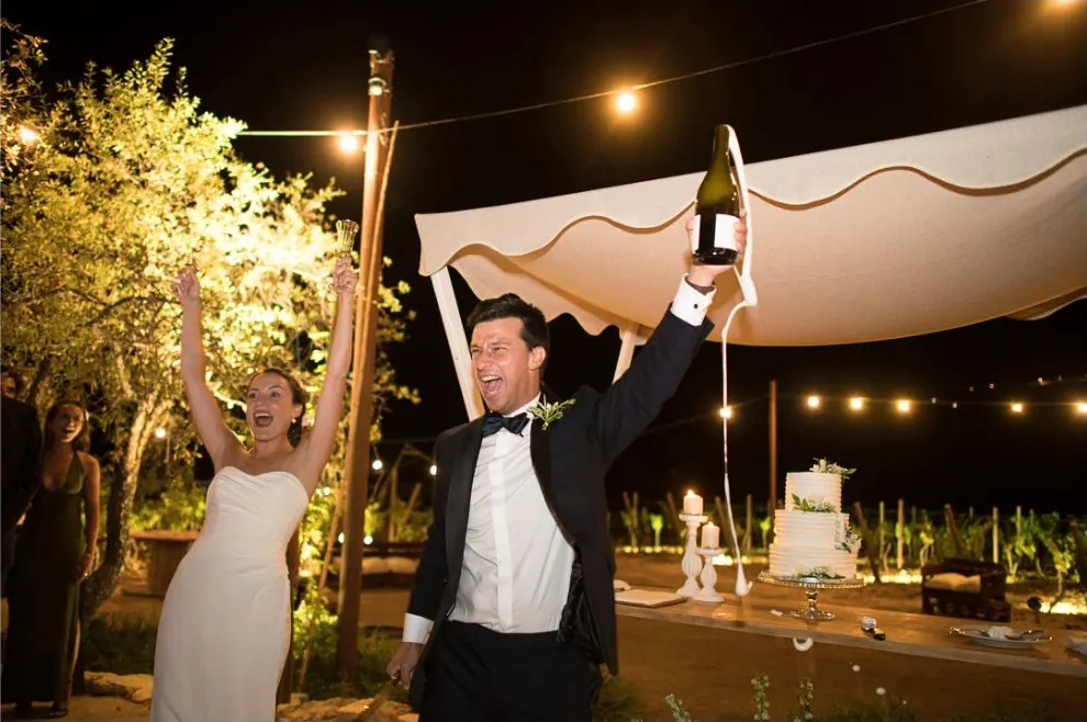 Novios celebrando por la noche con una botella de champán