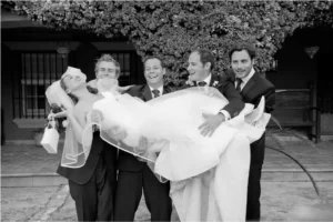 Amigos levantando a la novia en brazos, fotografía de boda en blanco y negro