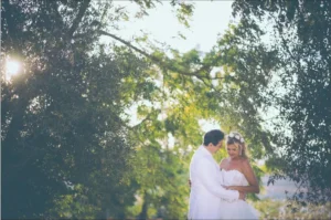 Novios abrazados bajo los árboles en la sesión de pareja de su boda