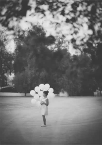 Niña con globos en el jardín durante una boda, fotografía en blanco y negro