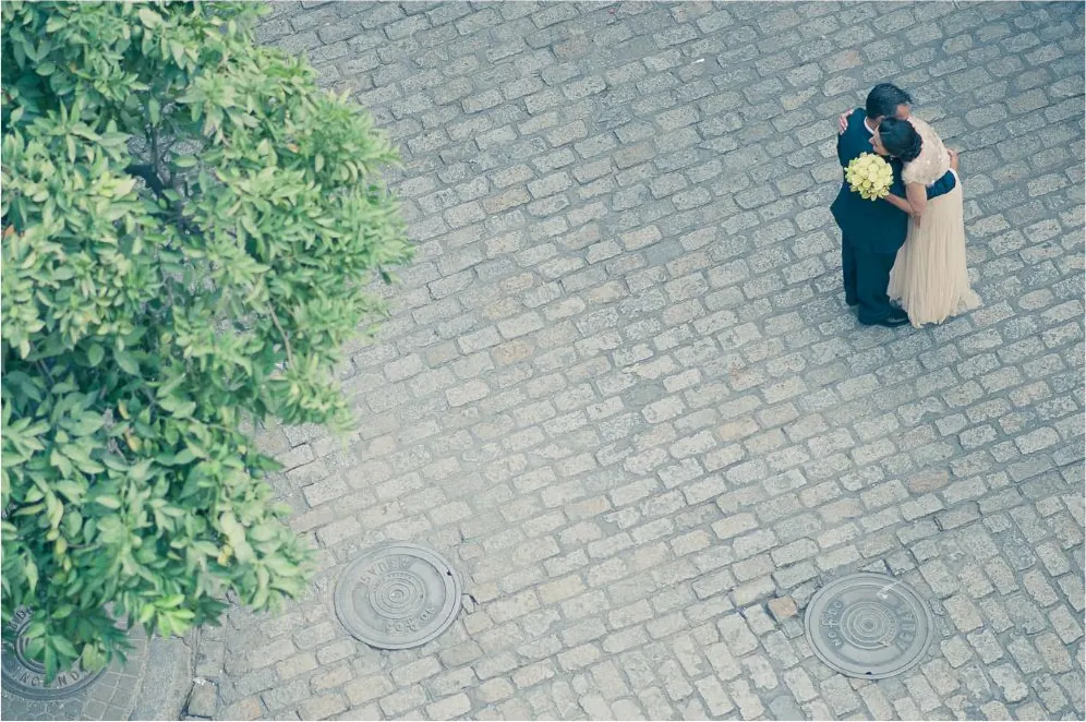 Pareja abrazada en una calle empedrada vista desde arriba