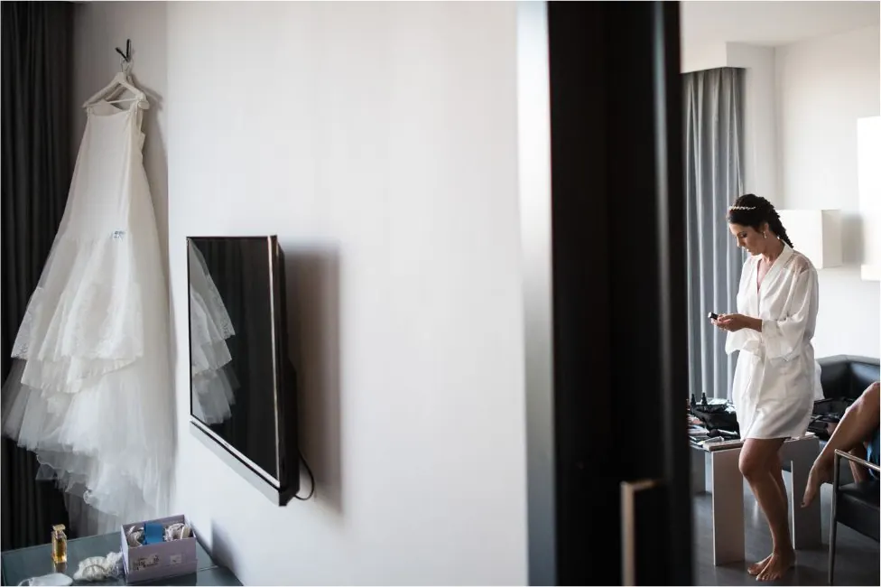 Novia preparándose en la habitación con el vestido colgado